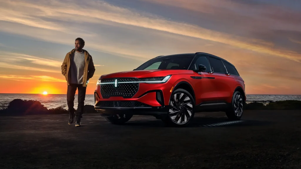 Stylish 2025 Lincoln Nautilus® SUV and man near beach during dramatic sunset.