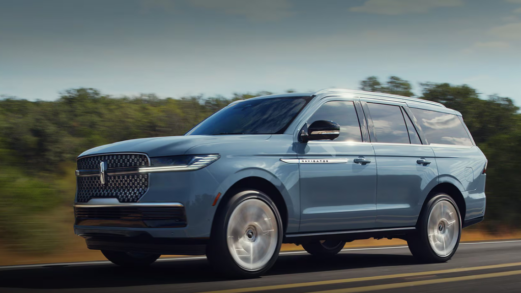 2025 Lincoln Navigator Reserve SUV in light blue driving on highway, showcasing bold grille, chrome accents, and luxury styling.