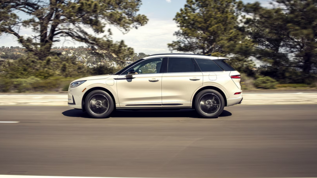 2025 Corsair® Grand Touring plug-in hybrid SUV driving on road with elegant modern body design.