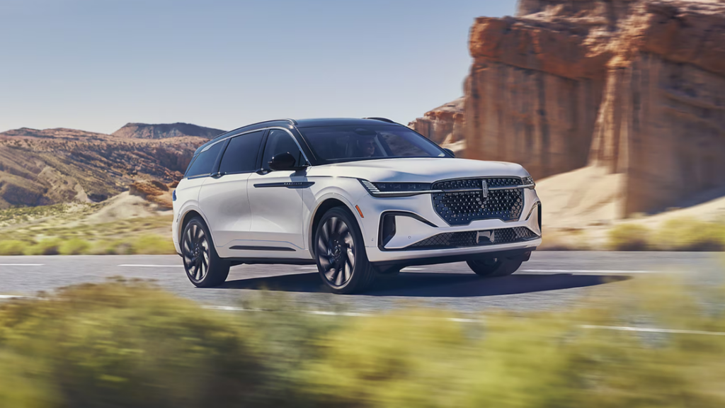 2026 Nautilus® SUV with refined front grille and LED headlights shown on open road with scenery.