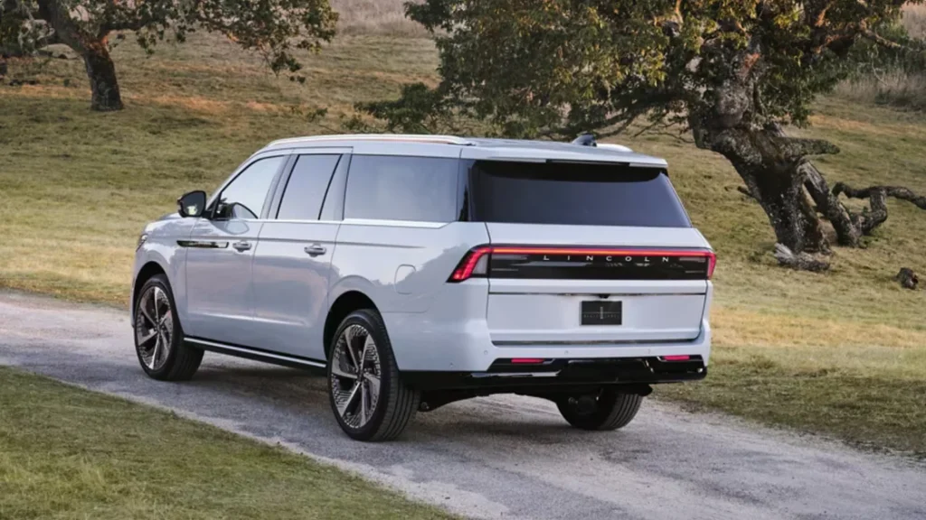 Rear view of a white 2025 Lincoln Navigator® Reserve SUV on a countryside path, emphasizing LED taillights.