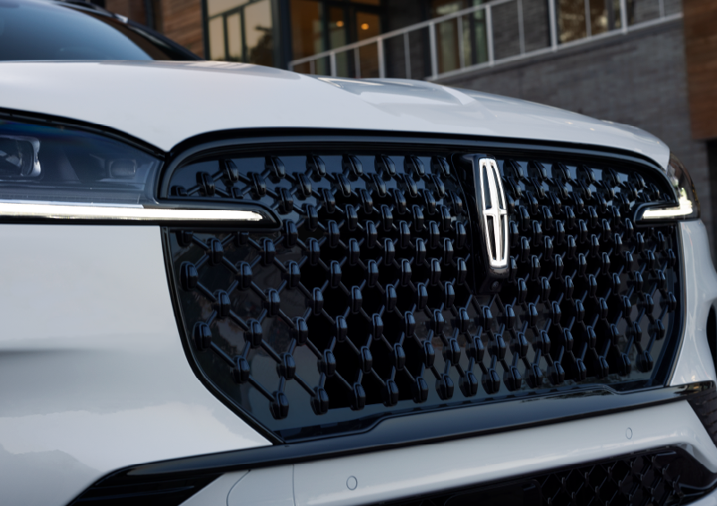 The black grille of a white 2025 Lincoln Aviator® SUV is shown with its fog lights on. | Nick Mayer Lincoln Mayfield in Mayfield Heights OH