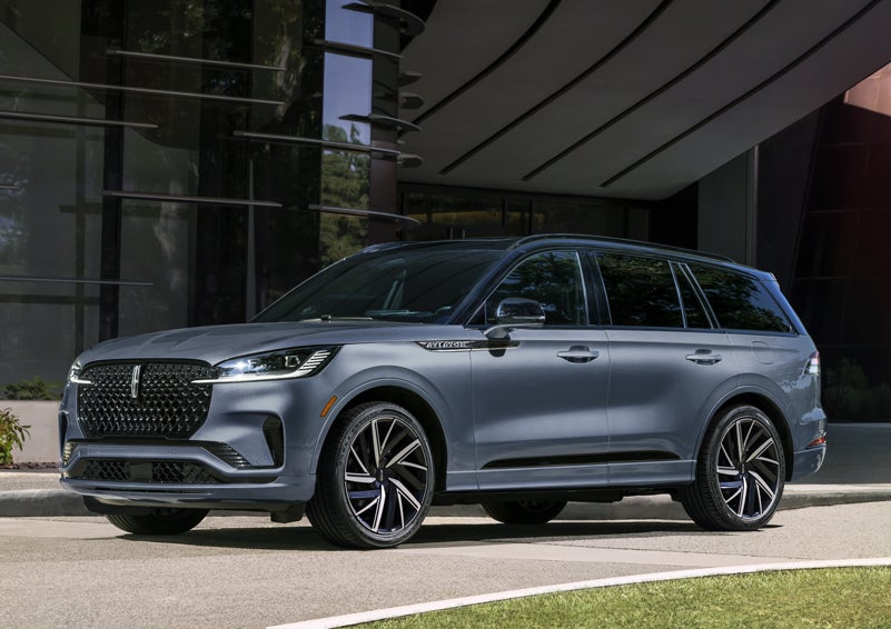 A gray 2025 Lincoln Aviator® SUV is parked outside a modern building showcasing the driver’s side of the vehicle. | Nick Mayer Lincoln Mayfield in Mayfield Heights OH