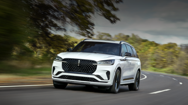 A white 2025 Lincoln Aviator® SUV is being driven down a road lined with trees. | Nick Mayer Lincoln Mayfield in Mayfield Heights OH