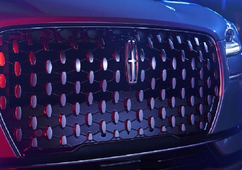 The grille of a 2025 Lincoln Corsair® SUV reflects neon light at night. | Nick Mayer Lincoln Mayfield in Mayfield Heights OH