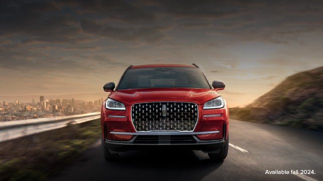 A 2025 red Lincoln Corsair® SUV is being driven down a road at sunset. | Nick Mayer Lincoln Mayfield in Mayfield Heights OH