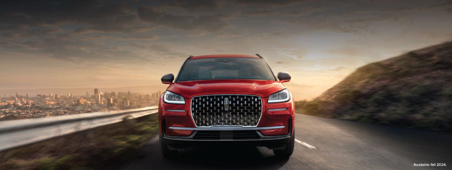A 2025 red Lincoln Corsair® SUV is being driven down a road at sunset. | Nick Mayer Lincoln Mayfield in Mayfield Heights OH