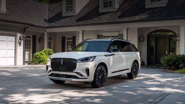 A white 2026 Lincoln Aviator® SUV is parked in the driveway of a luxury home. | Nick Mayer Lincoln Mayfield in Mayfield Heights OH