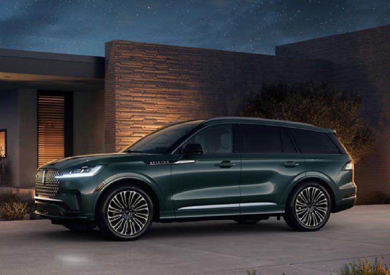 A green 2027 Lincoln Aviator® SUV is parked outside a contemporary home. | Nick Mayer Lincoln Mayfield in Mayfield Heights OH