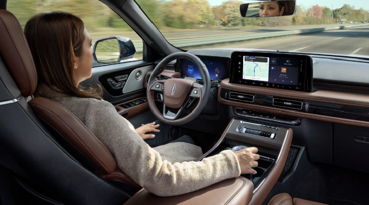 A 2027 Lincoln Aviator® SUV is being driven hands-free on a highway lined with trees. | Nick Mayer Lincoln Mayfield in Mayfield Heights OH