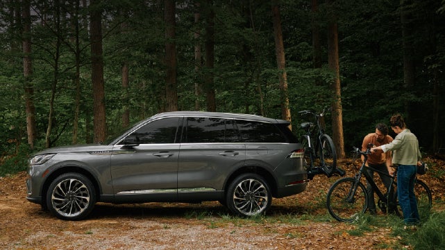 A father and son load e-bikes on a bike rack attached to a 2027 Lincoln Aviator® SUV. | Nick Mayer Lincoln Mayfield in Mayfield Heights OH