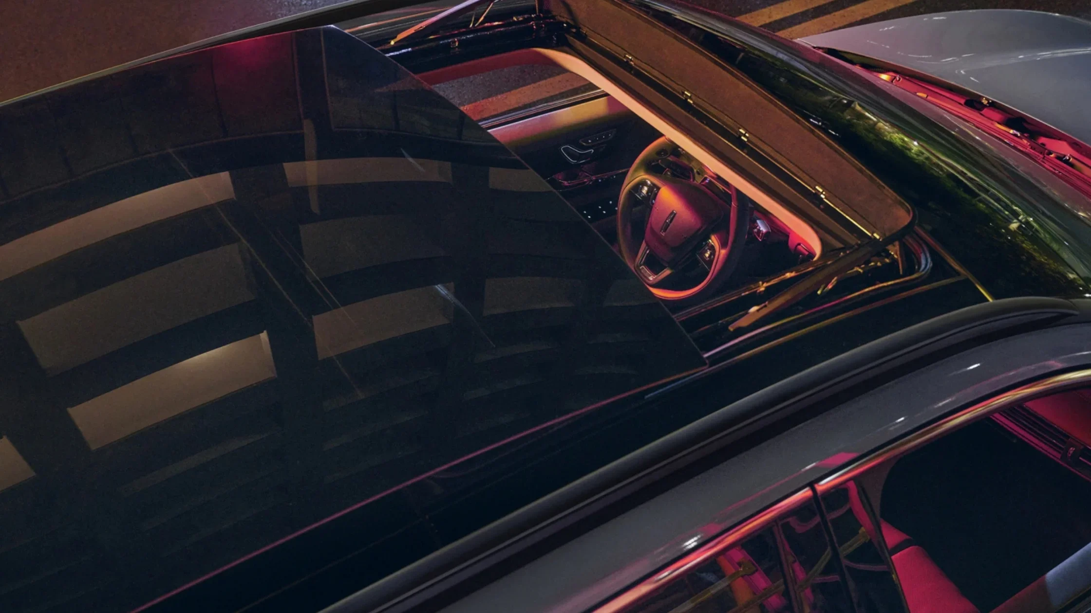 Panoramic roof view of 2025 Lincoln Corsair Grand Touring showing steering wheel and interior lighting from above.