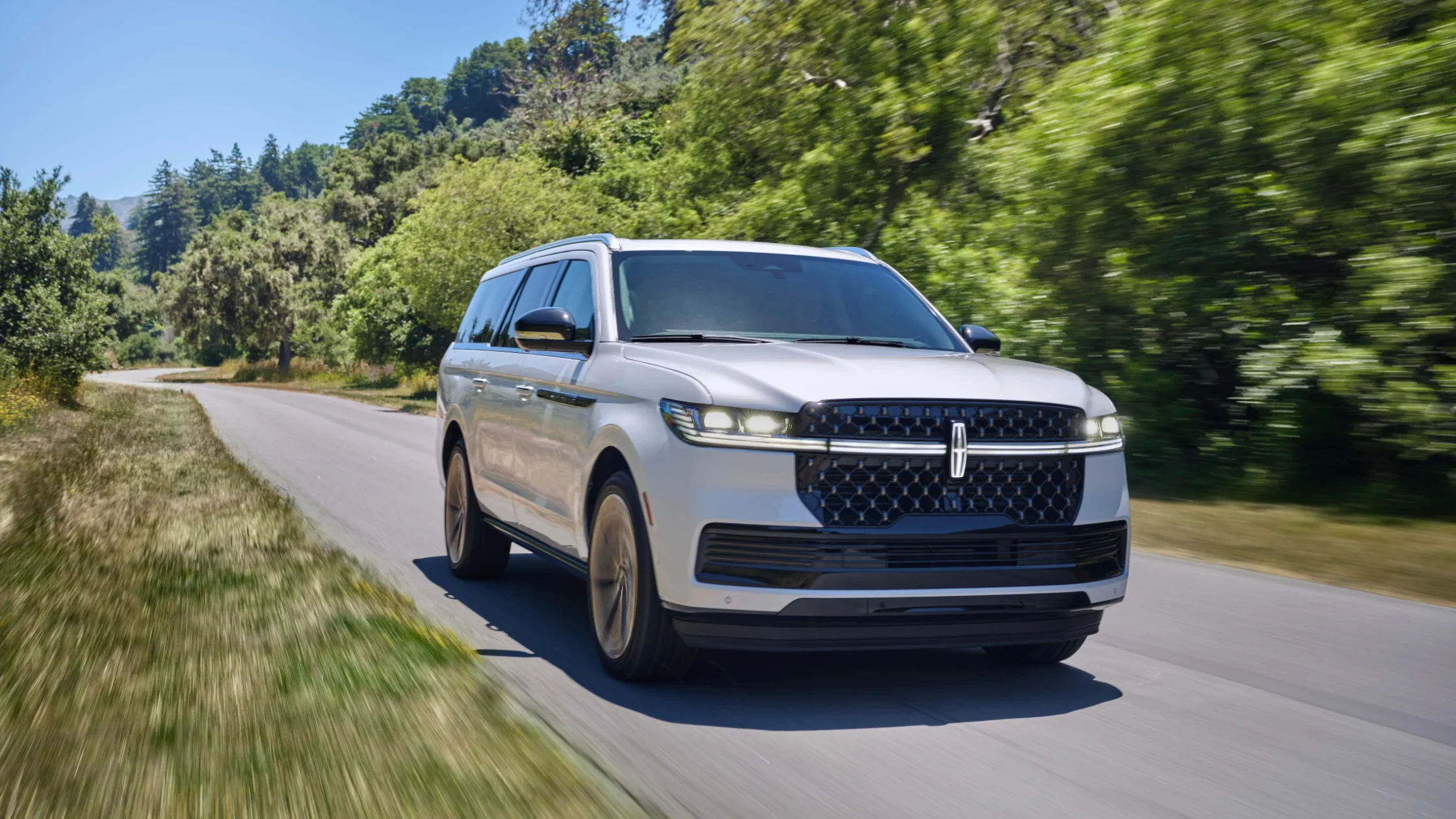 The 2025 Lincoln Black Label Navigator® driving on a scenic road, exuding elegance and power.
