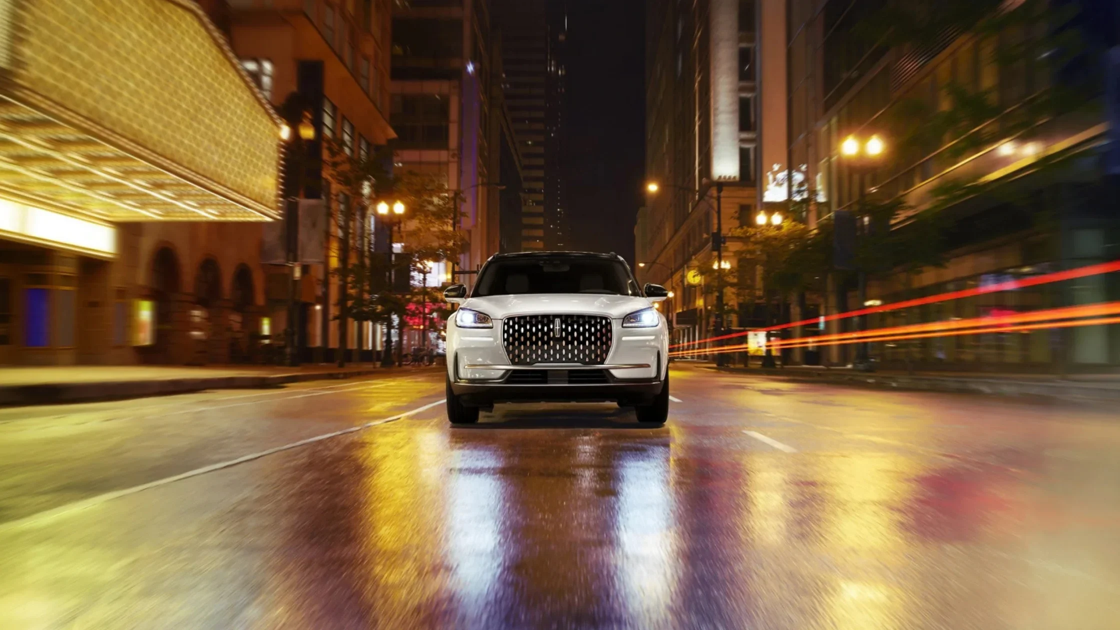 2025 Lincoln Corsair® in silver shown from the front driving on a wet city street at night