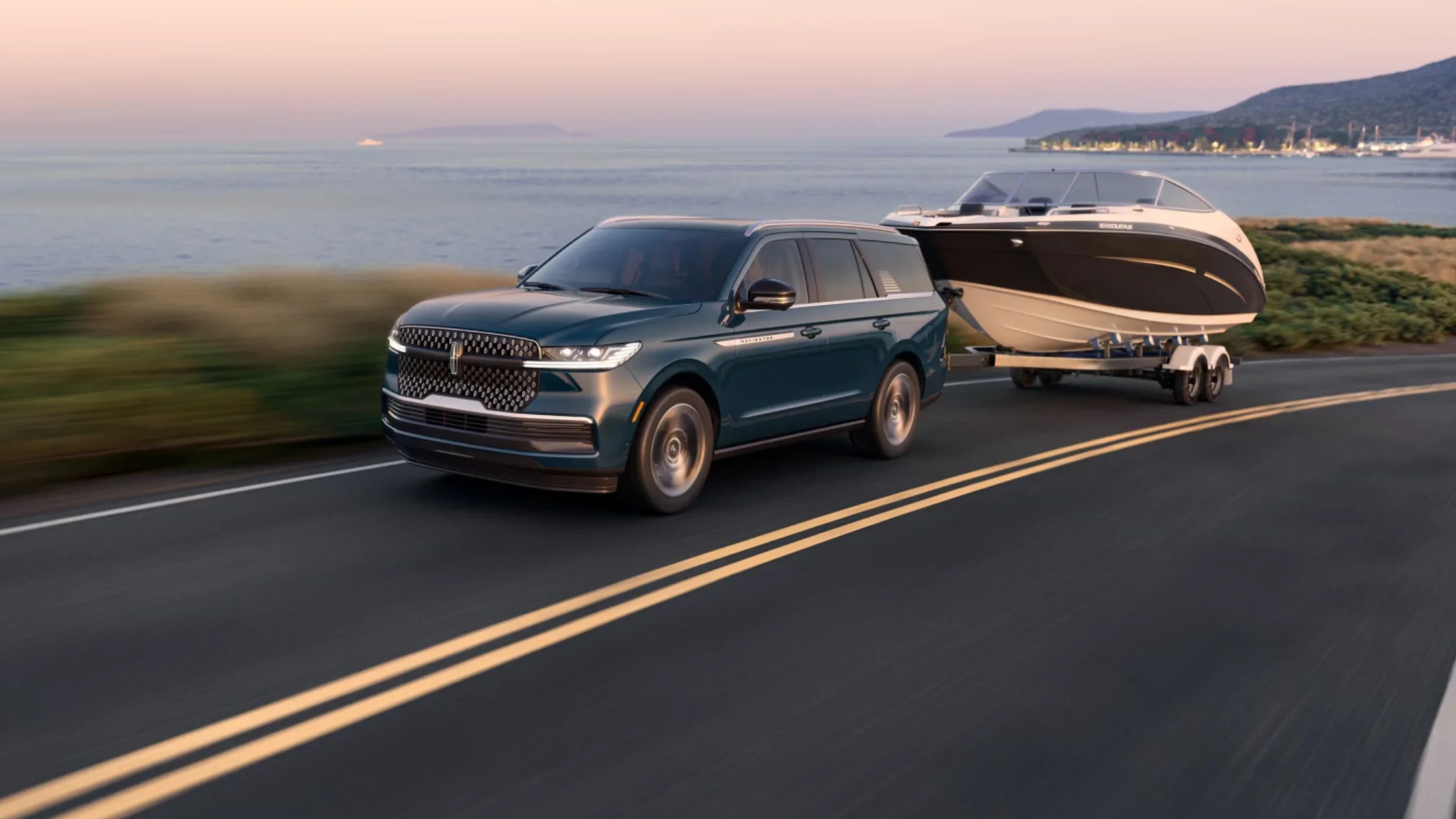 2025 Lincoln Navigator in green towing a boat on coastal road during sunset