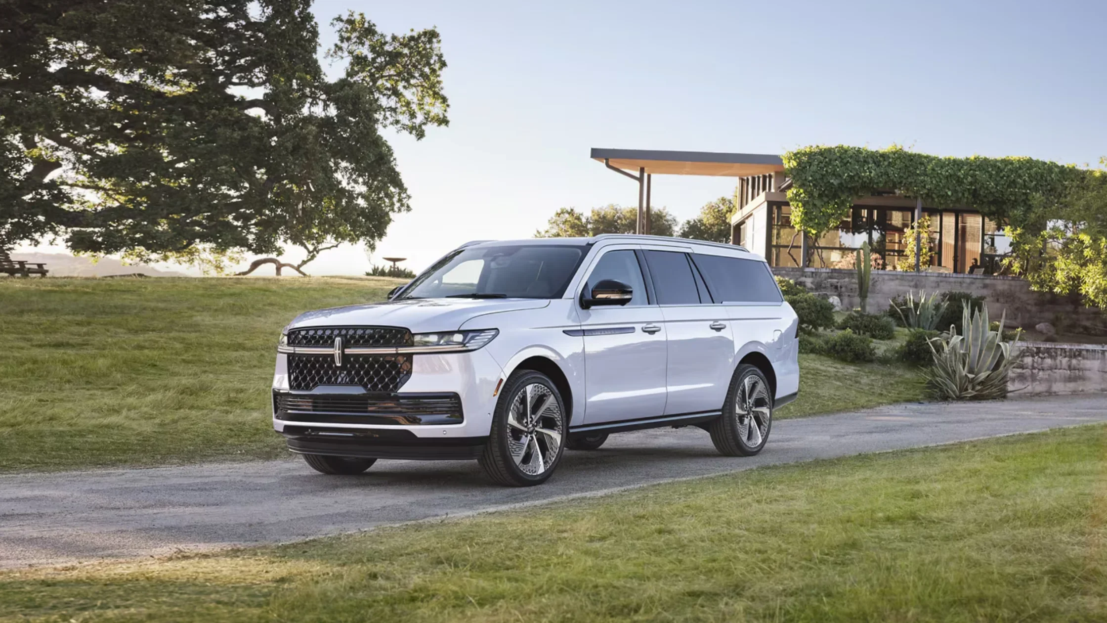 2025 Lincoln Navigator SUV in white parked near modern home with greenery in the background