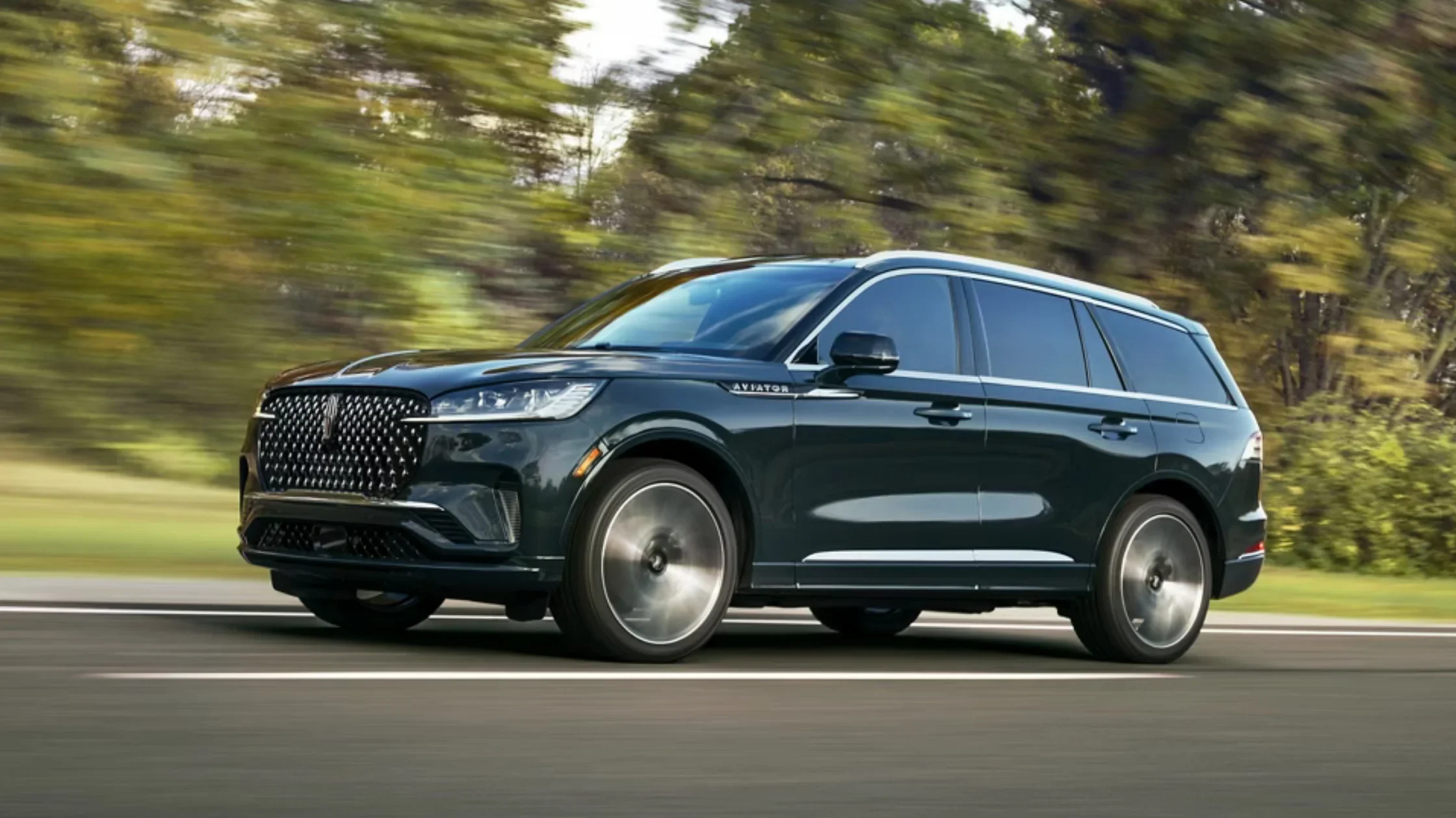 2025 Black Label Aviator driving on a forest road showcasing its sleek profile and modern styling.