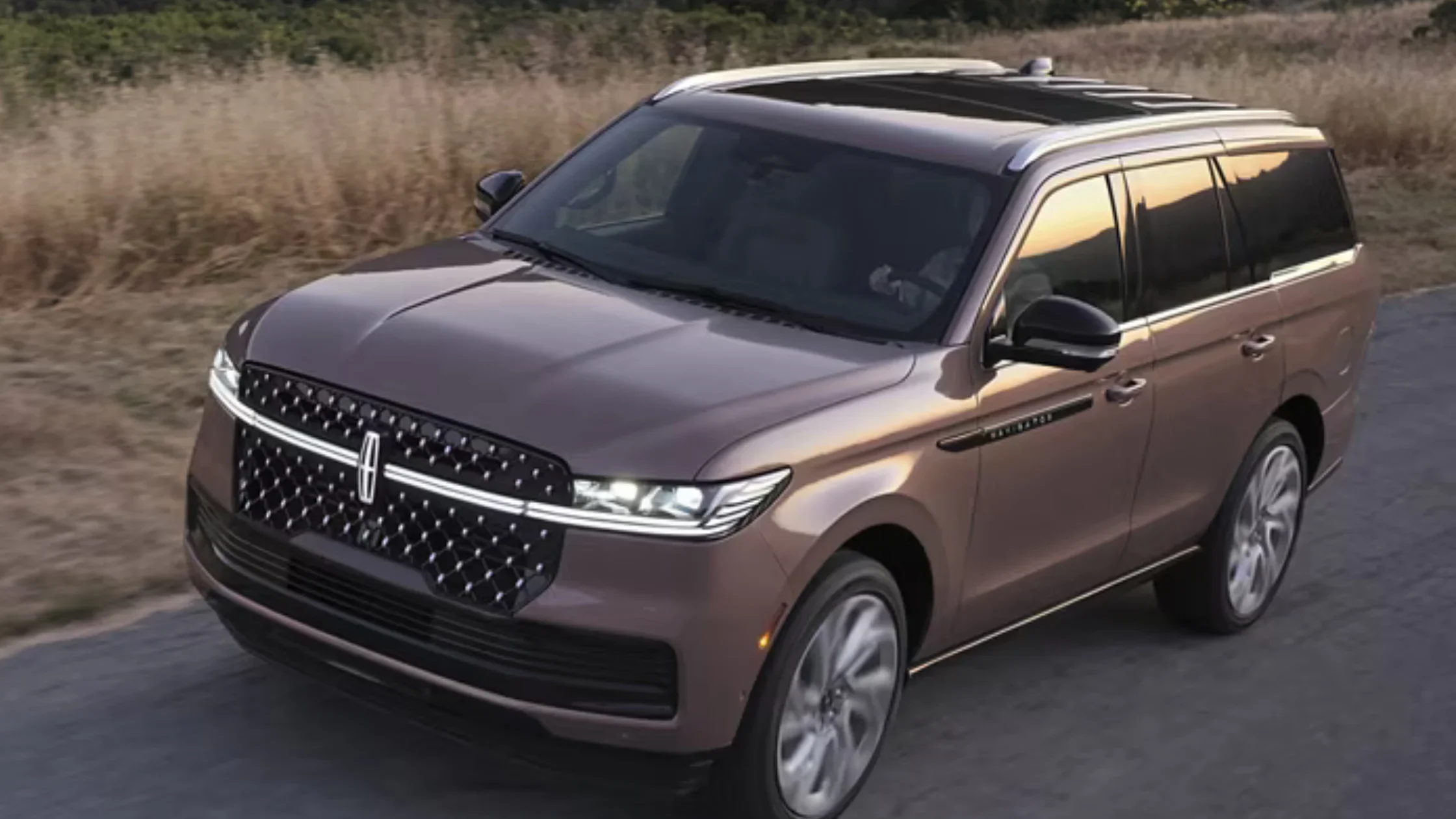 2025 Black Label Navigator SUV driving at sunset highlighting its bold grille and LED lighting.