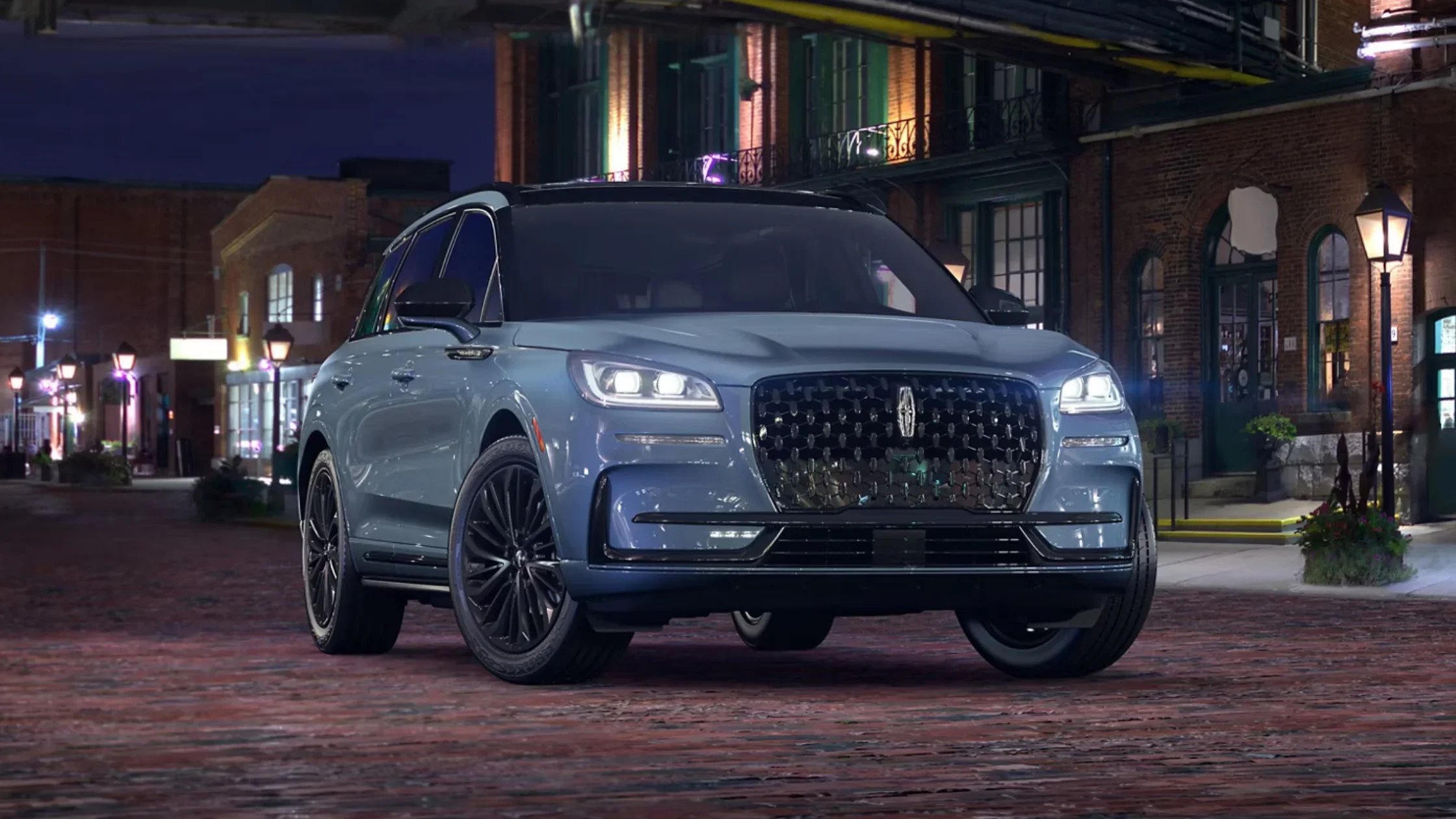 2025 Corsair® Grand Touring SUV in blue metallic finish parked on city brick street.