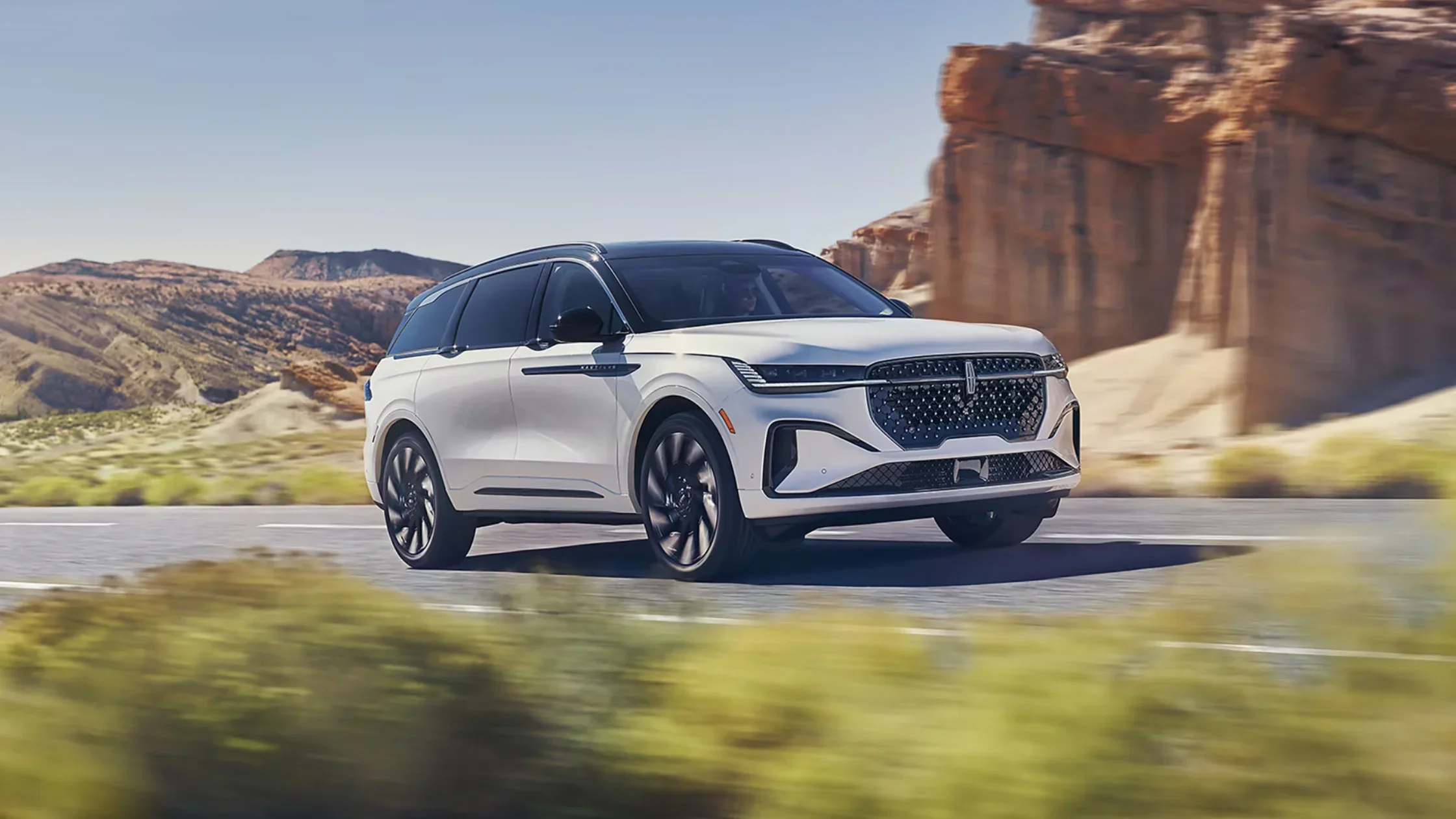 2026 Nautilus SUV in white driving through desert highway with signature Lincoln grille.